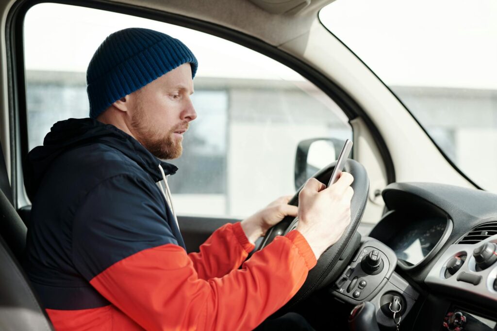 Distracted driver uses a smartphone in a car, highlighting road safety concerns.