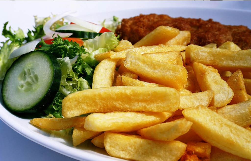 A digital air fryer with crispy fries and vegetables beside it