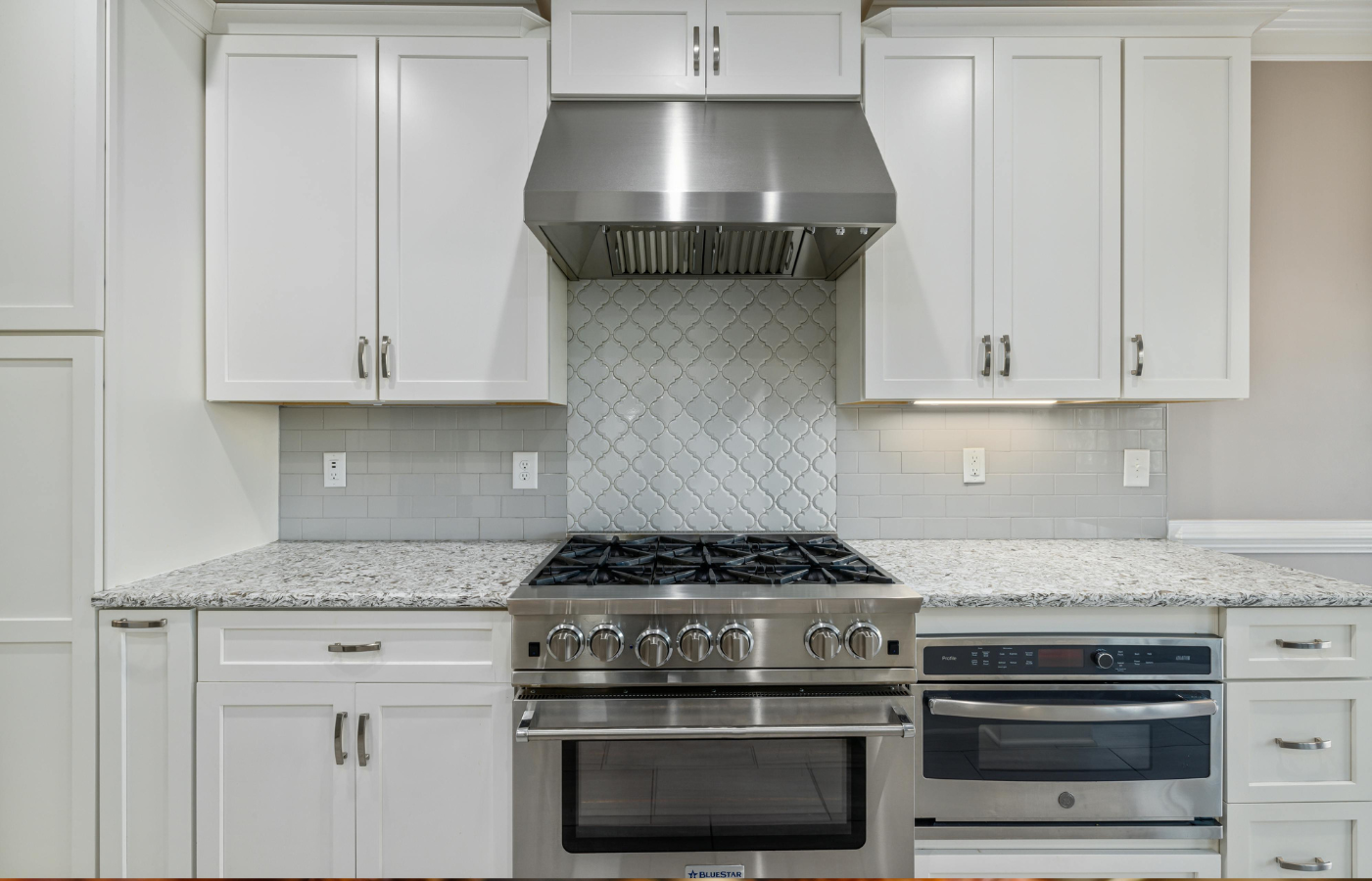 White Wooden Kitchen Cabinets Over Stainless Steel Gas Stove and Oven