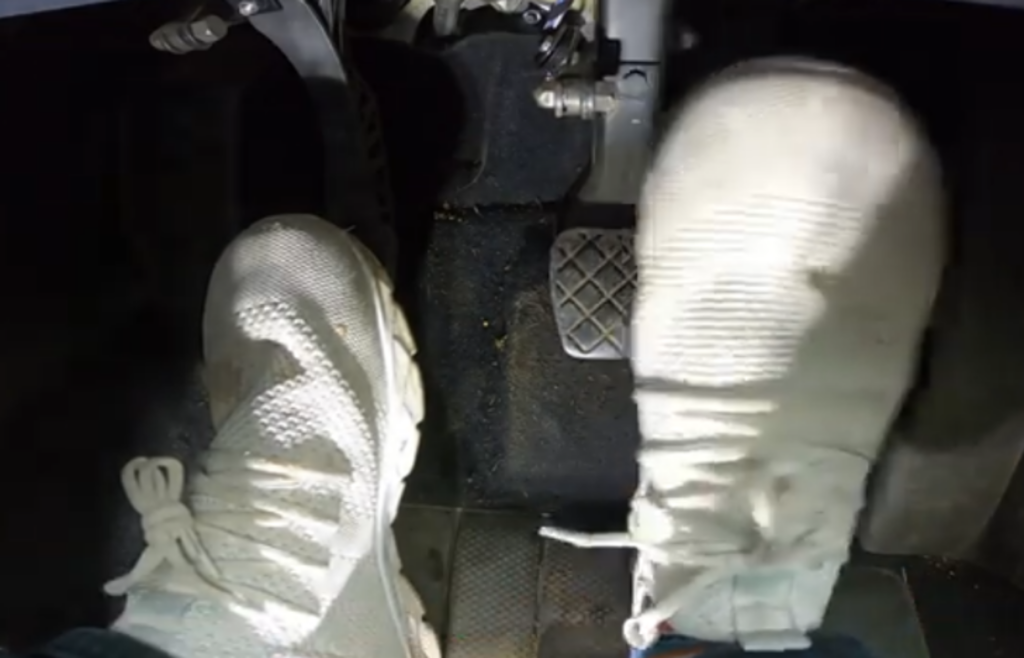 Driver’s foot hovering over clutch pedal