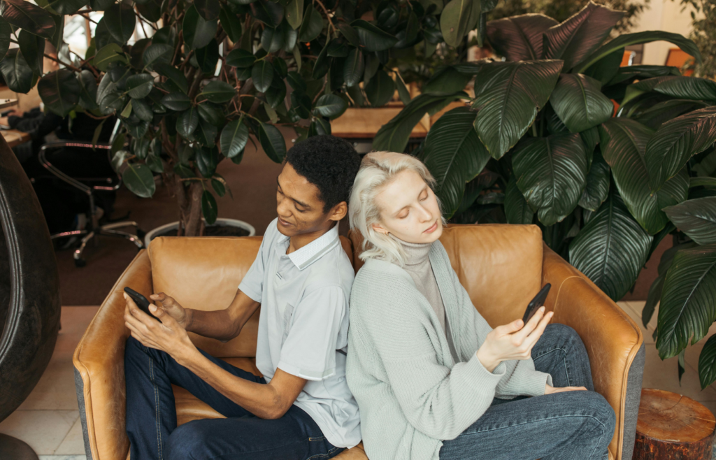 Man and Woman Sitting on Sofa While Using Cellphone