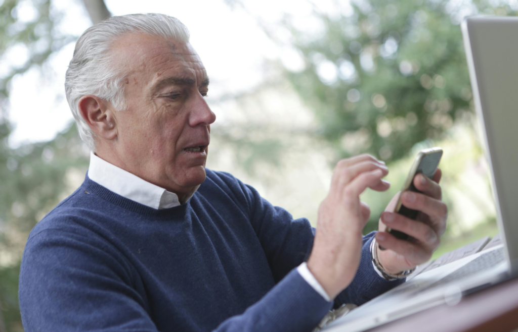 Man in Blue Sweater Holding Smartphone