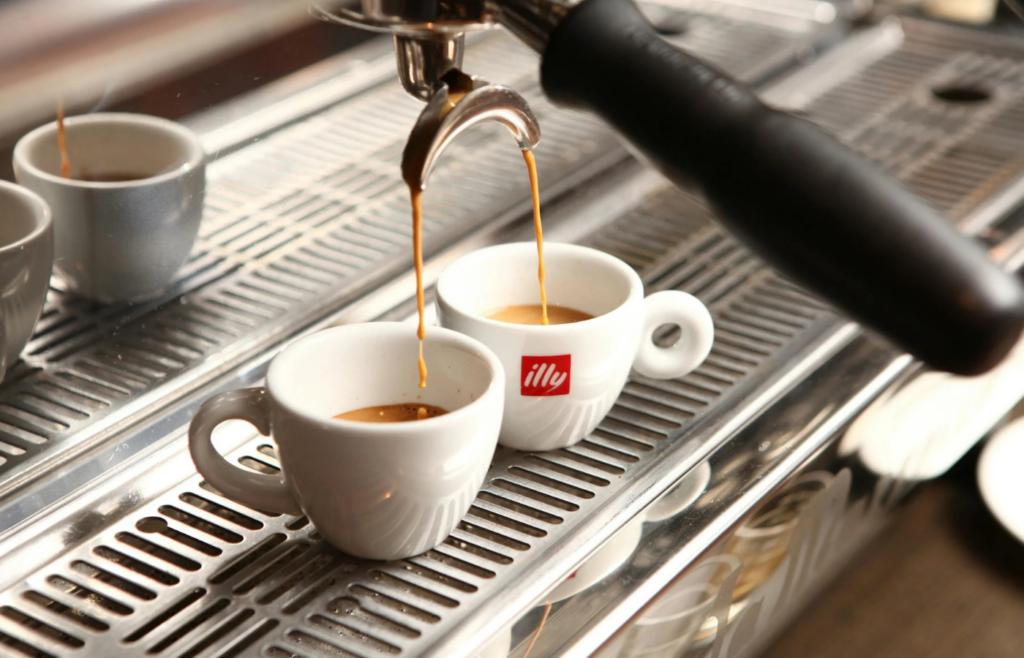 A coffee maker steaming with a fresh cup