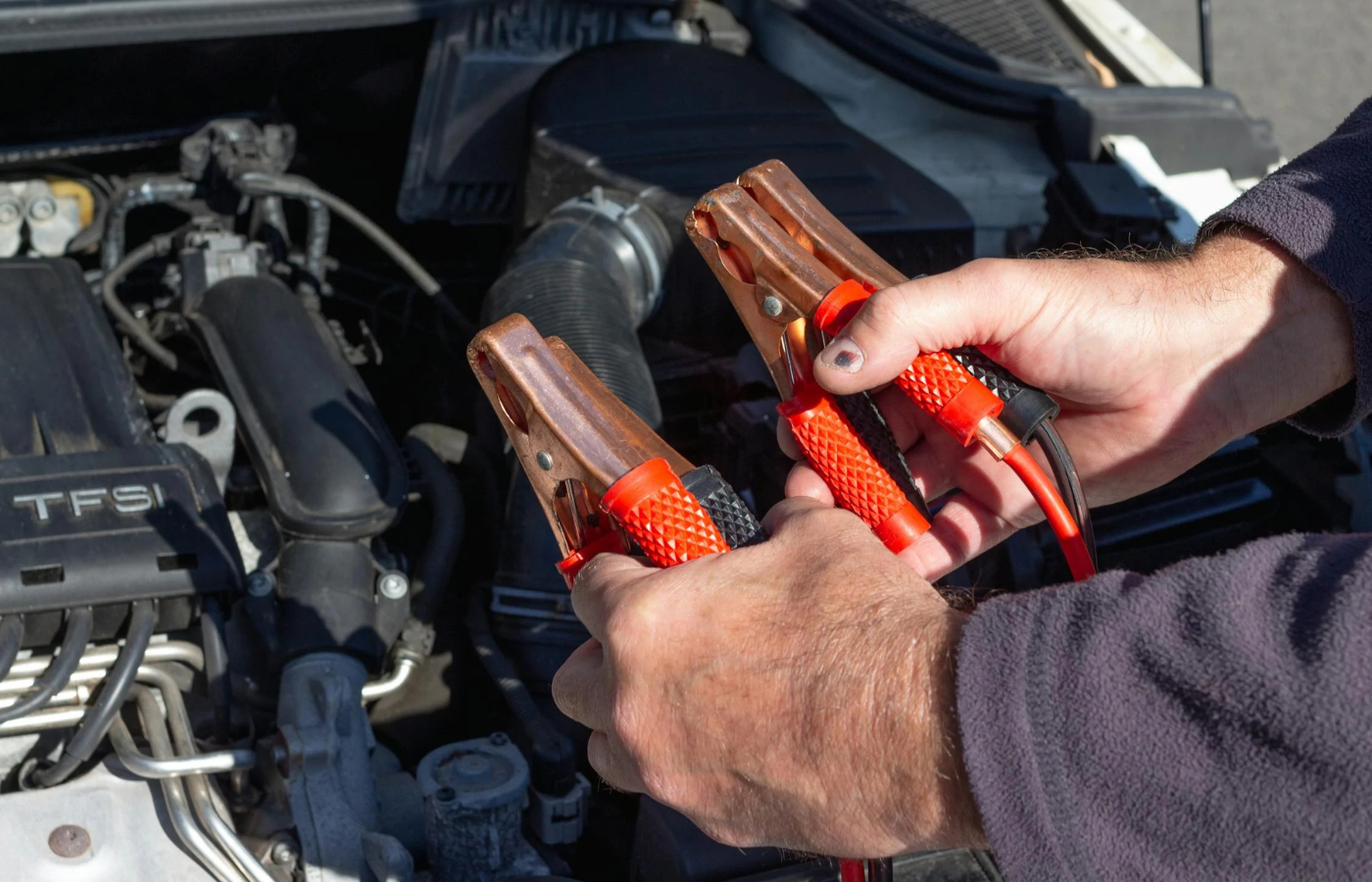 A dead car battery being jump-started