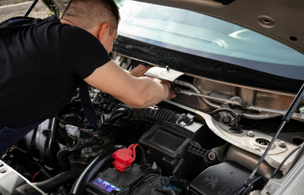 A person working under the hood in their driveway