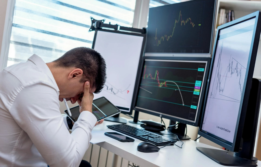 Office worker surrounded by multiple screens and devices