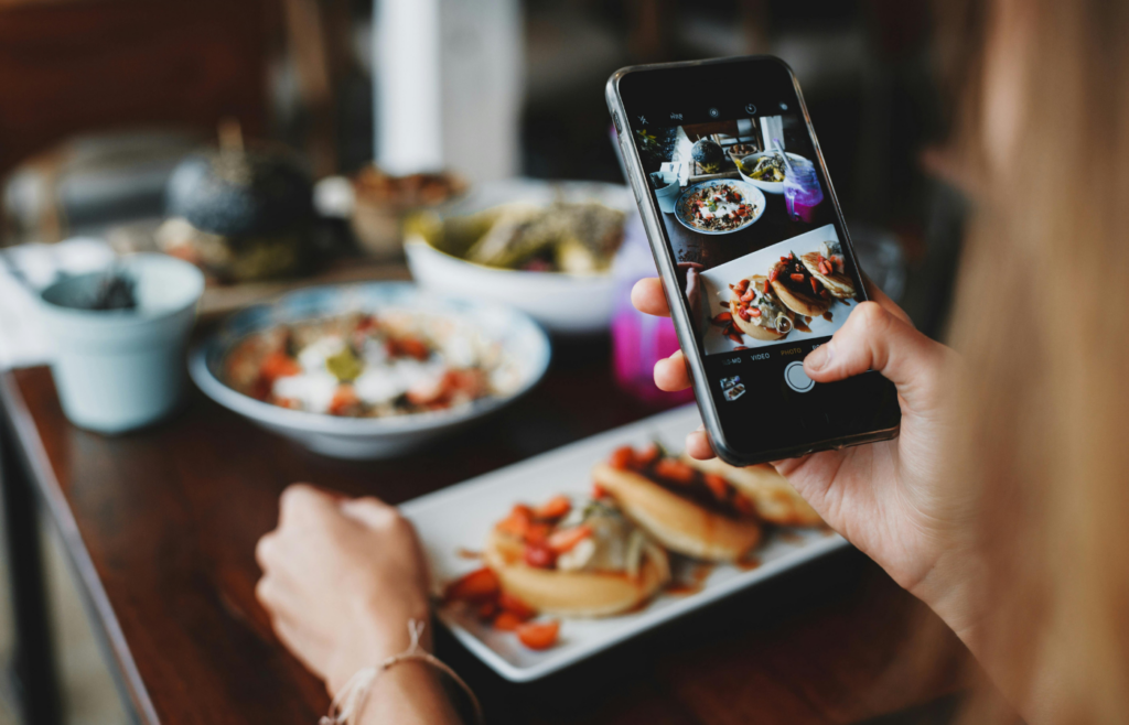 Crop woman taking shot of food on mobile phone during lunch