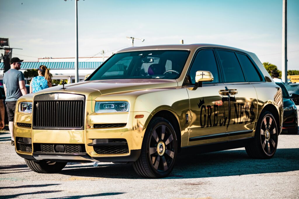 A gold rolls royce parked in a parking lot